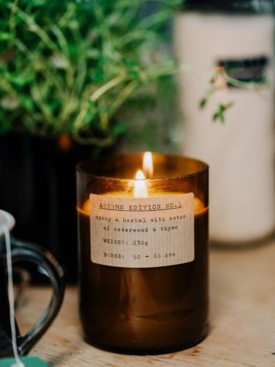 Large brown autumn candles lit in the kitchen with thyme and a cup of tea for a cosy autumn home. Beautiful candle gifts