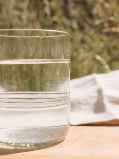 A clear recycled glass tumbler on a table outside in summer