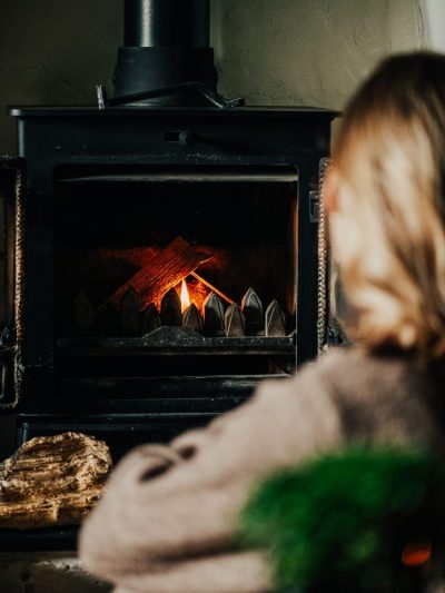 Creating cosy homes with a girl staring into a lit fire in a log burner