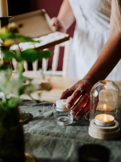 lady putting a natural tea light into a glass candle holder tea light holder with the box in her hand and a candle dome lit on the table