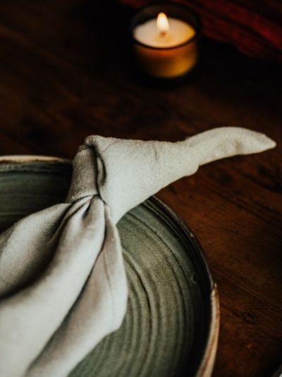 natural linen napkin knotted on a plate with a candle on the table