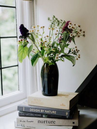 Glass vases curved olive green glass on a pile of books on a light and bright window sill