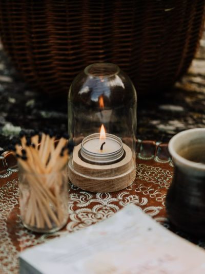 tea light holders clear glass dome with wooden base on a tray in the garden with a long matches pot and seasonal book