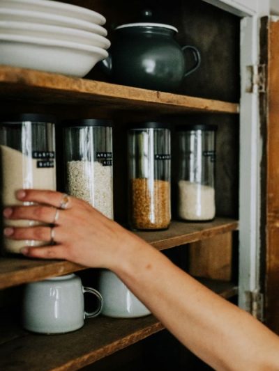 clear pantry jars in a cupboard with food stuff inside and someone reaching to pick one off the shelf. How to celebrate imbolc