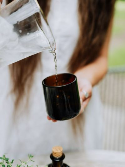 girl pouring water into a recycled repurposed amber brown glass