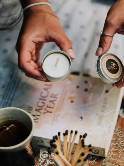 refillable candles tea light reusable metal tin in a woman's hand with long matches and a cup of tea
