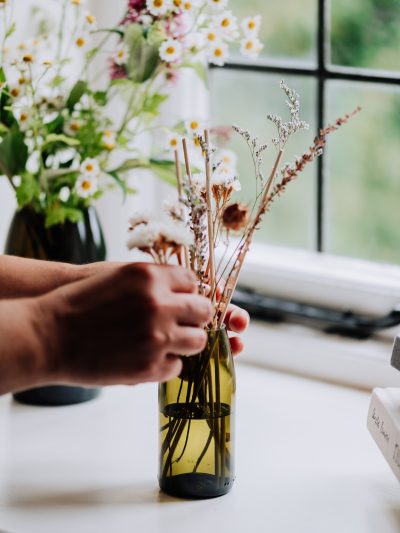 reed diffuser with recycled green glass vase being positioned on a window sill
